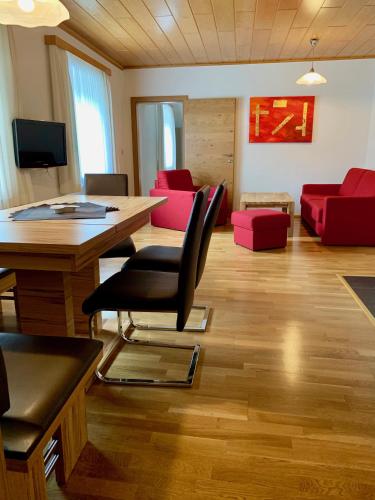 a living room with a table and red furniture at Ferienwelt Bogensperger in Mariapfarr