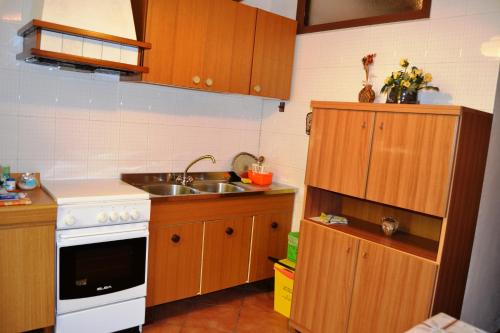una pequeña cocina con armarios de madera y fregadero en Aritzo appartamento romantico, en Aritzo