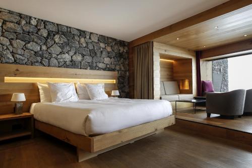 1 dormitorio con 1 cama grande y pared de piedra en chetzeron en Crans-Montana