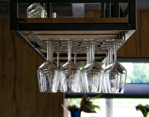 a bunch of wine glasses hanging from a rack at De la Rue Pipowagens in Sleeuwijk