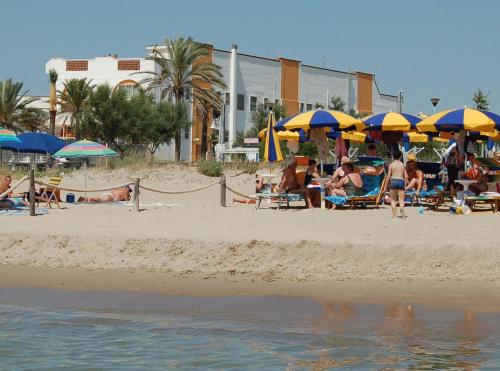 un grupo de personas en una playa con sombrillas en B&B L'Oasi, en Metaponto