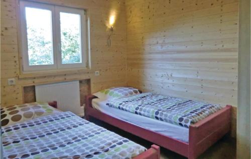 Cette chambre en bois comprend 2 lits et 2 fenêtres. dans l'établissement Chalet Bous - Breinchen, à Vianden