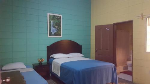 a bedroom with a bed and a blue wall at Guesthouse Dos Molinos B&B in San Pedro Sula