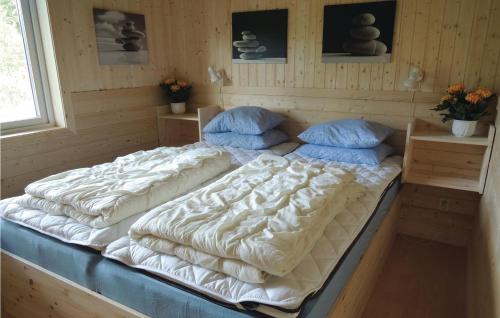 Cozy Home In Oskarstrm With Kitchen في Karlstorp: سرير كبير في غرفة مع وسادتين