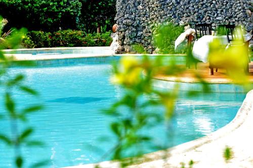 a swimming pool with a person sitting on a bench at Las Puertas del Paraíso in Río San Juan
