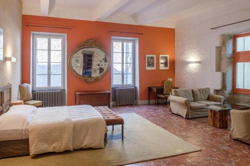 Caunes-MinervoisにあるHôtel Restaurant d'Alibertのオレンジ色の壁のベッドルーム1室、ベッド1台、ソファが備わります。