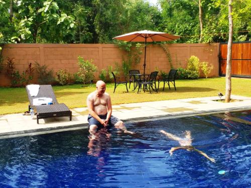 a man sitting in the water in a swimming pool at Honey Tree Polonnaruwa in Polonnaruwa