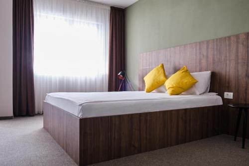 a bedroom with a large bed with yellow pillows at Boca Boutique Hotel in Timişoara