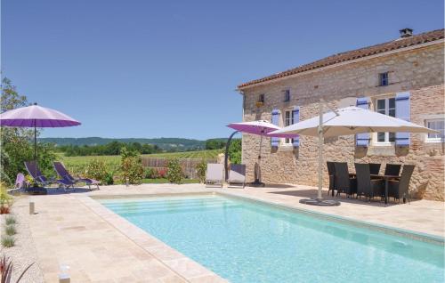 a pool with chairs and umbrellas next to a building at Cozy Home In Puy Levêque in Puy-lʼÉvêque