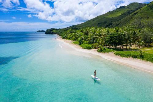 a person on a boat in the water near a beach at Malakati Village Beach House in Nacula Island