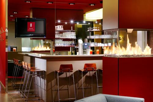 a bar in a restaurant with red chairs and a tv at Hotel Königstein in Munich