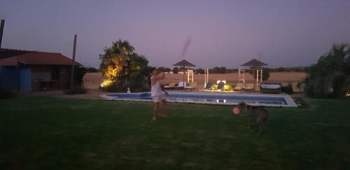 a woman playing frisbee with a dog in a yard at Quinta dos doze Sobreiros - Quarto Sol in Ferreira do Alentejo