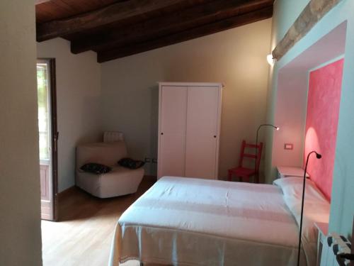 1 dormitorio con 1 cama blanca y 1 silla en La Colombaia, en Cascia