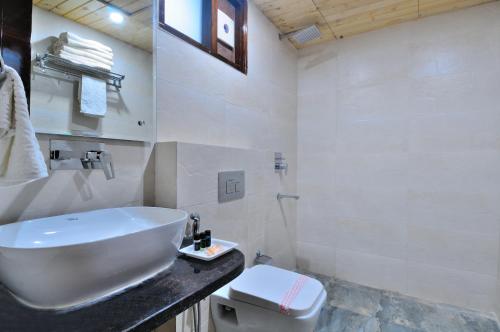 a white bathroom with a sink and a toilet at The Grand Uddhav in New Delhi