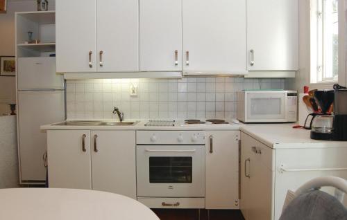 a kitchen with white cabinets and a sink and a microwave at Amazing Home In Skånes Fagerhult in Skånes Värsjö