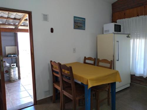 cocina con mesa, sillas y nevera en Departamento Loma Hermosa en Santa Rosa de Calamuchita