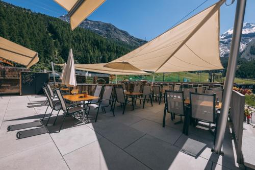 a patio with tables and chairs and umbrellas at Apart Lodge belMont in Saas-Fee