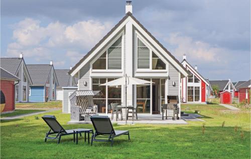 a house with chairs and an umbrella in the grass at 2 Bedroom Lovely Home In Zerpenschleuse in Zerpenschleuse