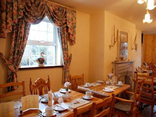 a dining room with a wooden table and a window at Hawthorn House Guesthouse in Kenmare