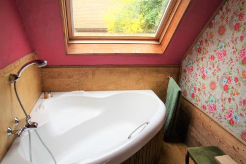 a bathroom with a white tub and a window at Amberhoeve in Schorisse