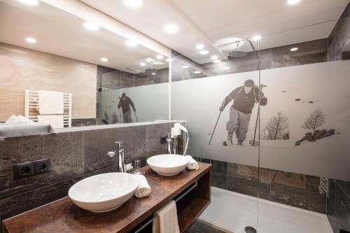 a bathroom with two sinks and a mirror at Genusshotel Alpenblick in Längenfeld