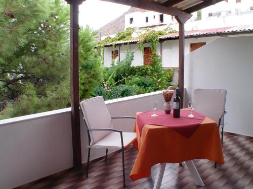斯卡拉的住宿－Sunset，阳台上配有一张桌子、两把椅子和一张红色的桌布