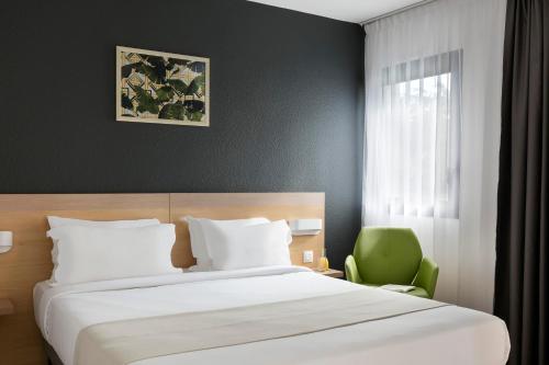 a bedroom with a bed and a green chair at Citadines Austerlitz Paris in Paris