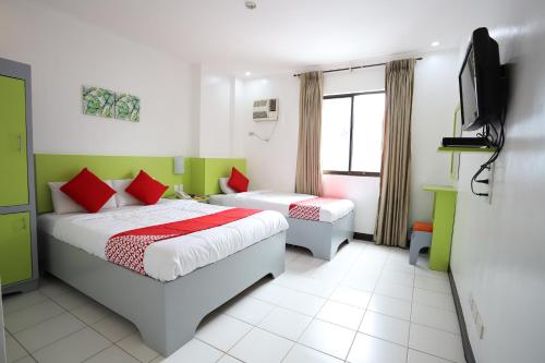 a bedroom with two beds and a flat screen tv at OYO 210 Apple Tree Suites in Cebu City