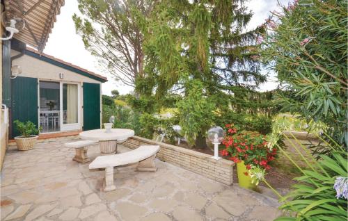 un patio avec une table et deux bancs et des fleurs dans l'établissement 1 Bedroom Awesome Home In Visan, à Visan