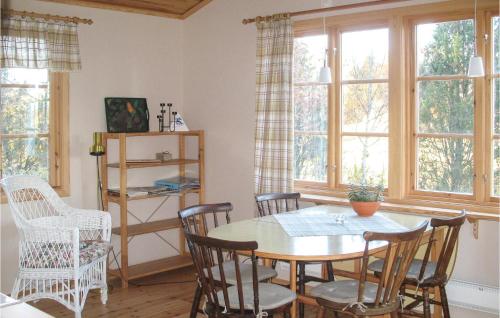 - une salle à manger avec une table, des chaises et des fenêtres dans l'établissement Gorgeous Home In Silverdalen With Kitchen, à Silverdalen