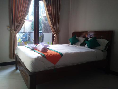a bedroom with a large bed with green and red pillows at Homestay Purbalingga Tengah Kota by Simply Homy in Purbolinggo