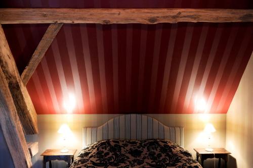 a bedroom with a red and white striped wall at Les Confidences de Messire Sanglier, stylished guest houses in Beauraing