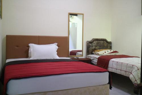 a bedroom with two beds and a mirror at The Homey Rooms and Tours in Yogyakarta