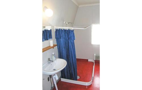 a bathroom with a sink and a blue shower curtain at Holiday Home Förenäs Eksjö in Berghemmet