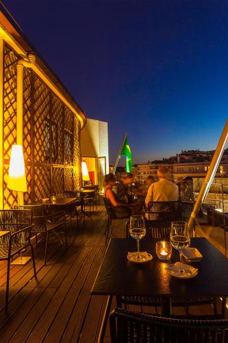 people sitting at tables on a balcony at night at Pao de Acucar Hotel in Porto