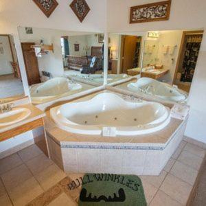 baño grande con 2 lavabos y bañera grande en Bullwinkles Rustic Lodge en Poplar Bluff