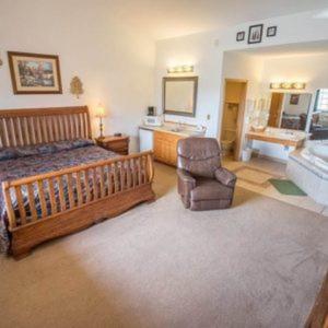 1 dormitorio con cama, silla y lavamanos en Bullwinkles Rustic Lodge en Poplar Bluff
