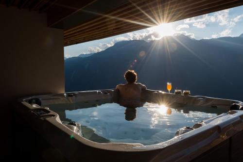 a man sitting in a bath tub with the sun shining at Berghotel Chäserstatt in Ernen