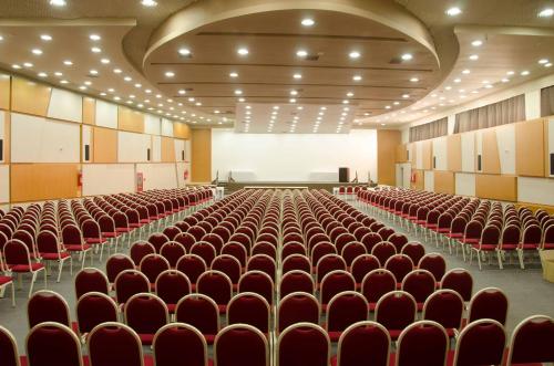 an empty lecture hall with red chairs and a stage at Hotel Sibara SPA & Convenções in Balneário Camboriú
