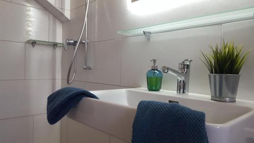 Baño blanco con lavabo y toalla azul en Ferienwohnung Eisenring in idyllischer Umgebung, en Gähwil