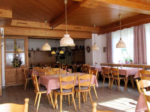 a dining room with tables and chairs and pendant lights at Landgasthof Zur Mühle in Naila