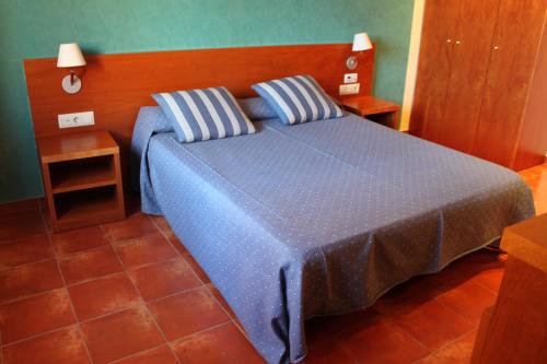 a blue bed with two pillows in a bedroom at Hotel Picasso in Torroella de Montgrí