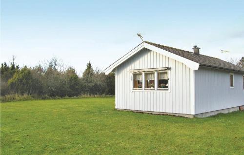 una pequeña casa blanca en un campo de hierba en Stunning Home In Lttorp With Kitchen en Löttorp