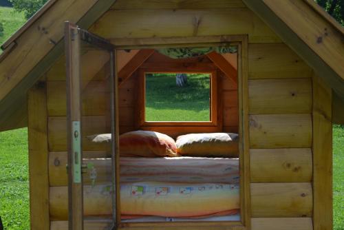 a bed in a wooden house with a window at Tara Place - Camp Rabrenovic in Mojkovac