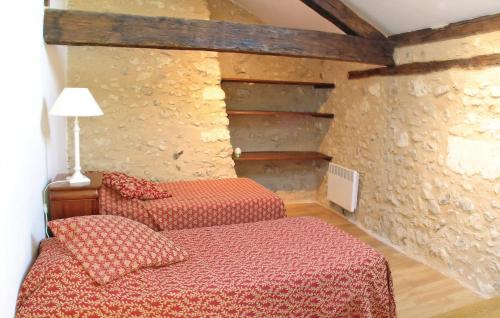une chambre avec deux lits et un mur en pierre dans l'établissement 2 Bedroom Nice Home In Grignols, à Grignols