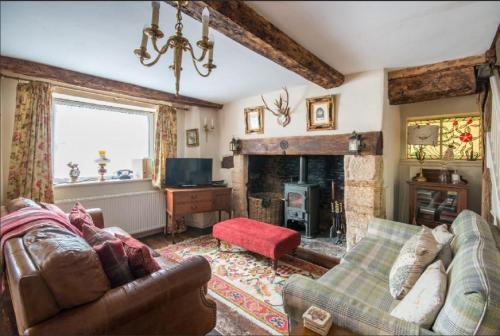 a living room with a couch and a fireplace at Tudor Cottage in Fairford