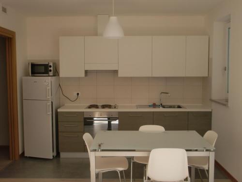 - une cuisine avec des placards blancs, une table et des chaises dans l'établissement Residence Villa Susy, à Duino