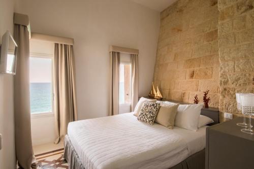 a bedroom with a large bed with a large window at Dimora Talenti in Polignano a Mare