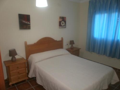 1 dormitorio con cama blanca y cortinas azules en Casa Detrés en Cogollos de Guadix