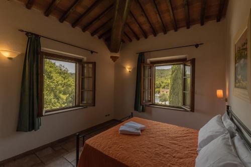 a bedroom with a bed and two windows at Borgo Mulignone in Casole dʼElsa